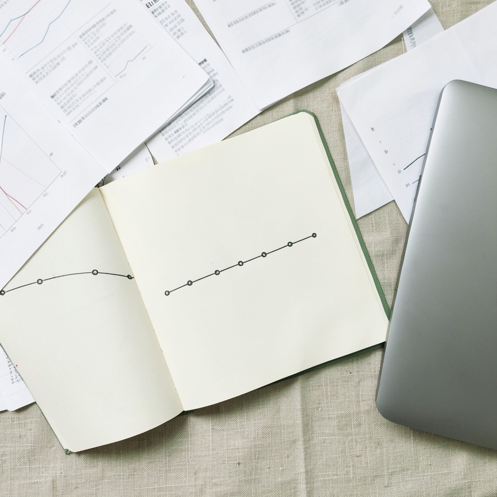 Notebook and printed process timeline on a desk beside a laptop
